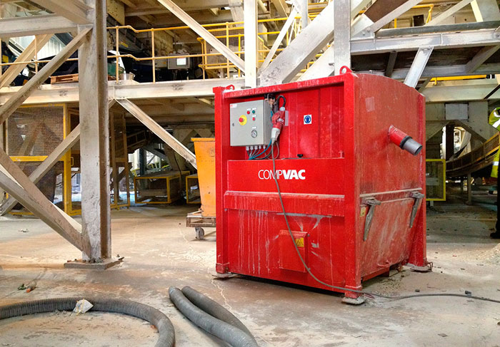 Red DISAB CompVac industrial vacuum unit installed in a dusty factory setting with metal support structures.