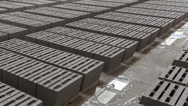 Concrete blocks on a wet factory floor with ventilation units used to remove dust from the concrete production process.
