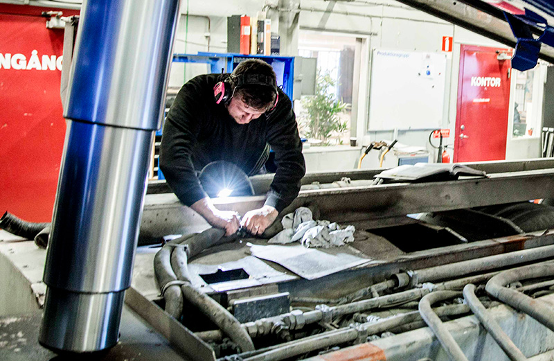 Technician performing maintenance or inspection inside a DISAB RoRoVac™ SEL vacuum unit, emphasizing service accessibility and workplace safety in industrial cleaning systems.