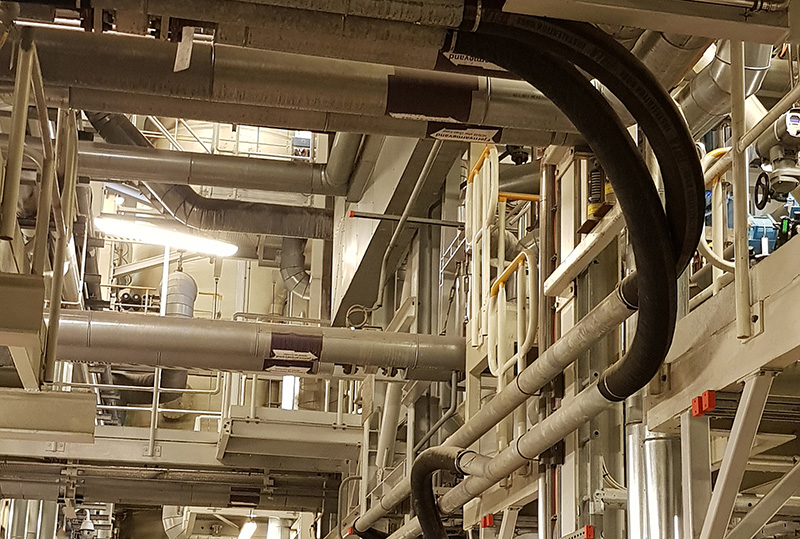 Complex network of suspended industrial vacuum hoses and piping inside a facility, showcasing the integration potential of the DISAB SEBF-III unit in fixed vacuum systems.