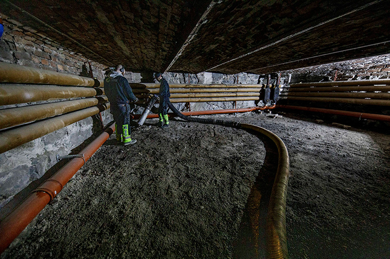 Industrial workers operating DISAB hoses in a confined underground tunnel, demonstrating the vacuum system's suitability for high-suction material collection in demanding environments such as mining, concrete, and surface treatment.